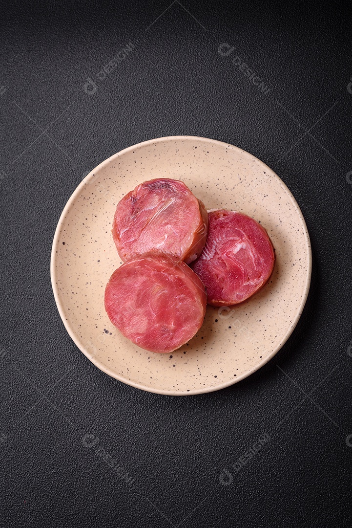 Bifes redondos de atum suculento cru com sal e especiarias sobre um fundo escuro de concreto