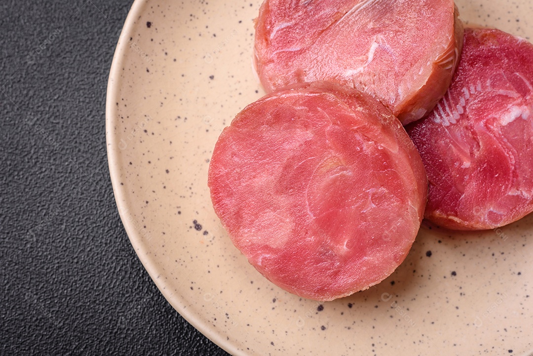 Bifes redondos de atum suculento cru com sal e especiarias sobre um fundo escuro de concreto