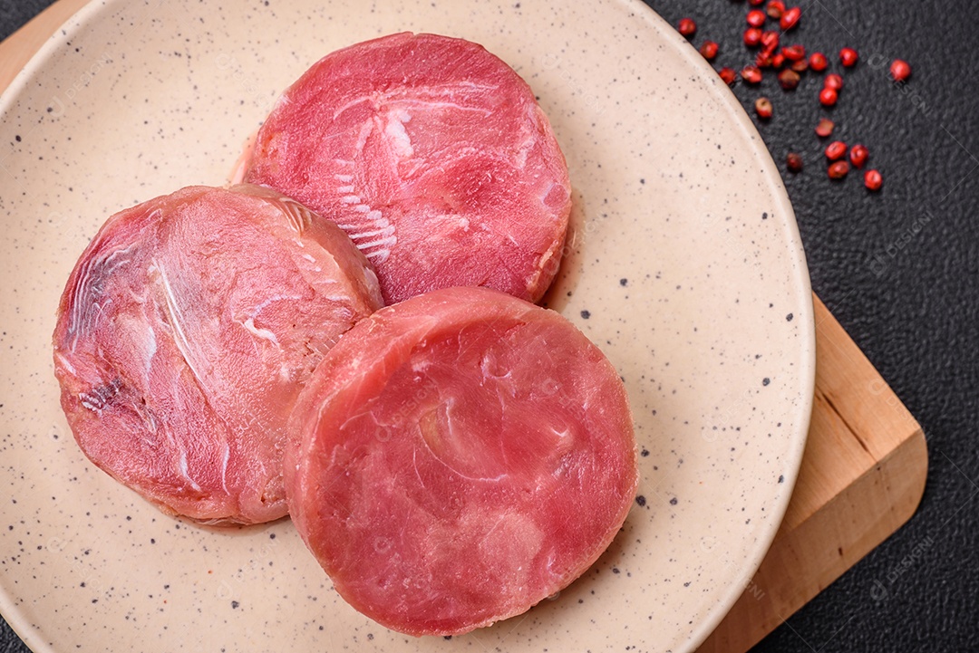 Bifes redondos de atum suculento cru com sal e especiarias sobre um fundo escuro de concreto