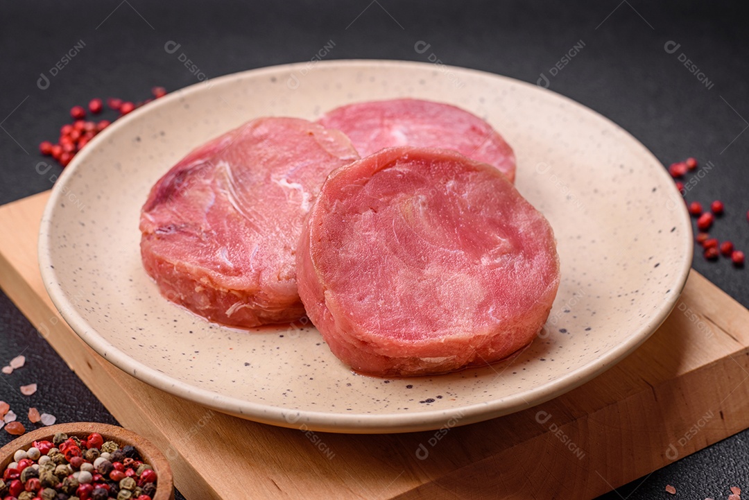 Bifes redondos de atum suculento cru com sal e especiarias sobre um fundo escuro de concreto