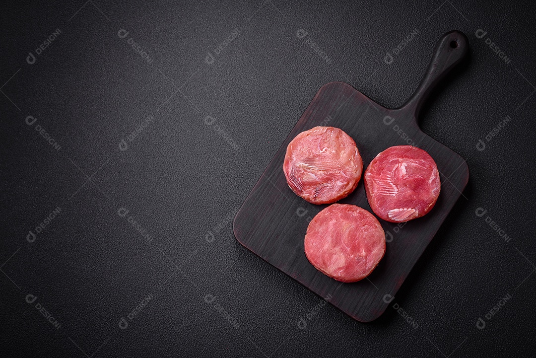 Bifes redondos de atum suculento cru com sal e especiarias sobre um fundo escuro de concreto