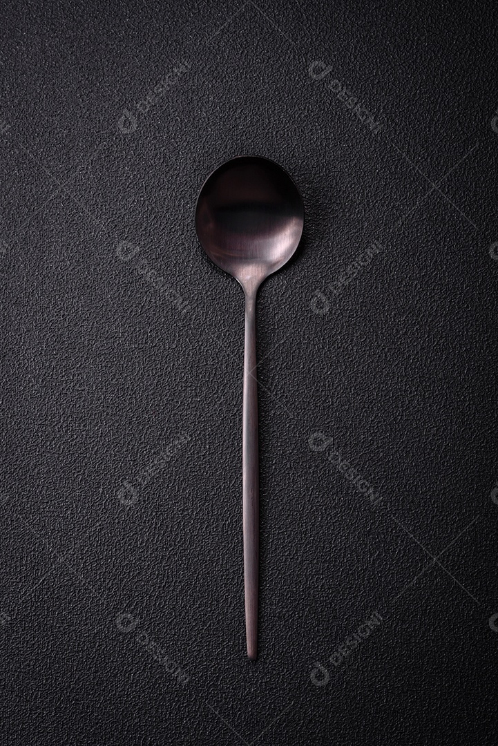 Colher de metal vazia em fundo de concreto texturizado escuro. Talheres, preparação para o jantar