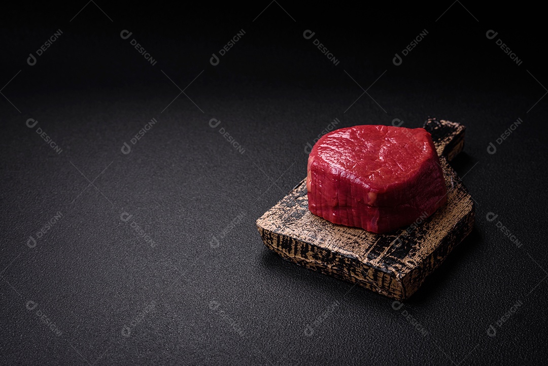 Carne crua fresca e suculenta com sal, especiarias e ervas sobre um fundo de concreto texturizado escuro