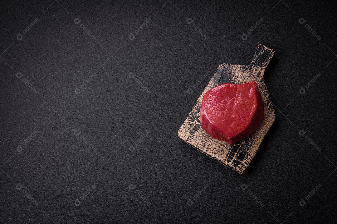 Carne crua fresca e suculenta com sal, especiarias e ervas sobre um fundo de concreto texturizado escuro