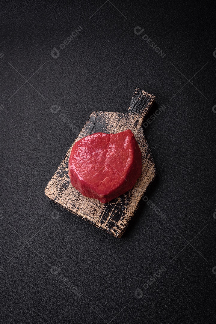 Carne crua fresca e suculenta com sal, especiarias e ervas sobre um fundo de concreto texturizado escuro