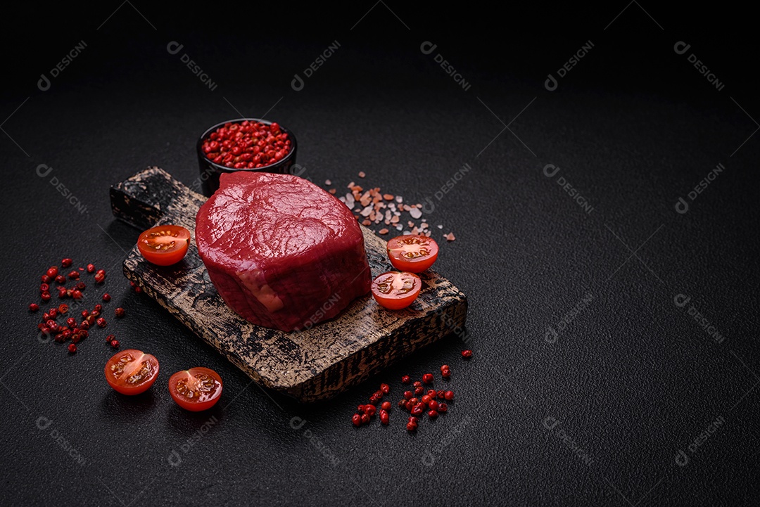 Carne crua fresca e suculenta com sal, especiarias e ervas sobre um fundo de concreto texturizado escuro