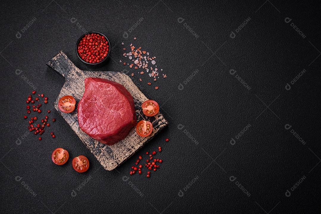 Carne crua fresca e suculenta com sal, especiarias e ervas sobre um fundo de concreto texturizado escuro