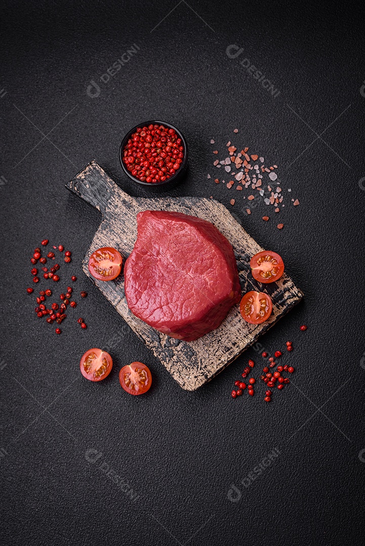 Carne crua fresca e suculenta com sal, especiarias e ervas sobre um fundo de concreto texturizado escuro