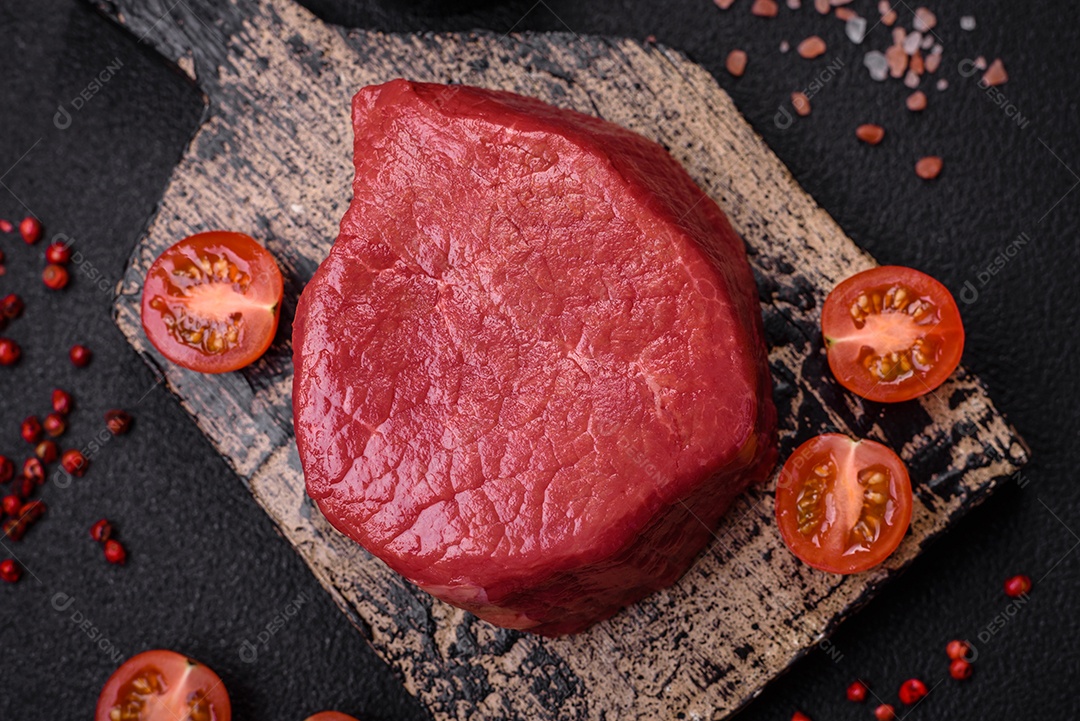 Carne crua fresca e suculenta com sal, especiarias e ervas sobre um fundo de concreto texturizado escuro