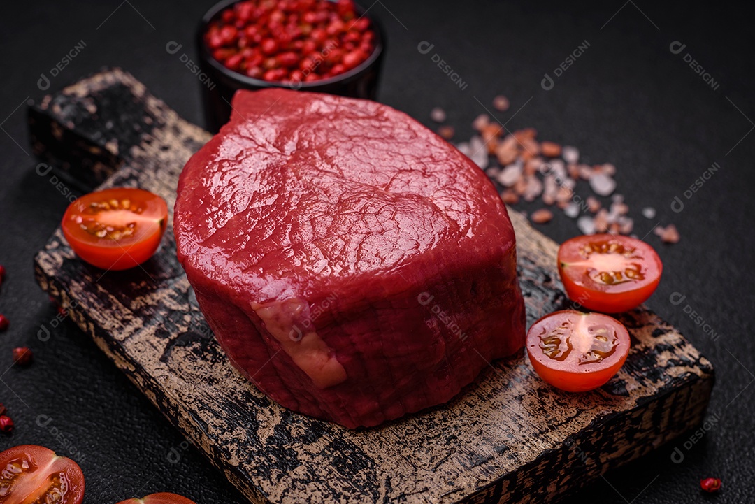 Carne crua fresca e suculenta com sal, especiarias e ervas sobre um fundo de concreto texturizado escuro