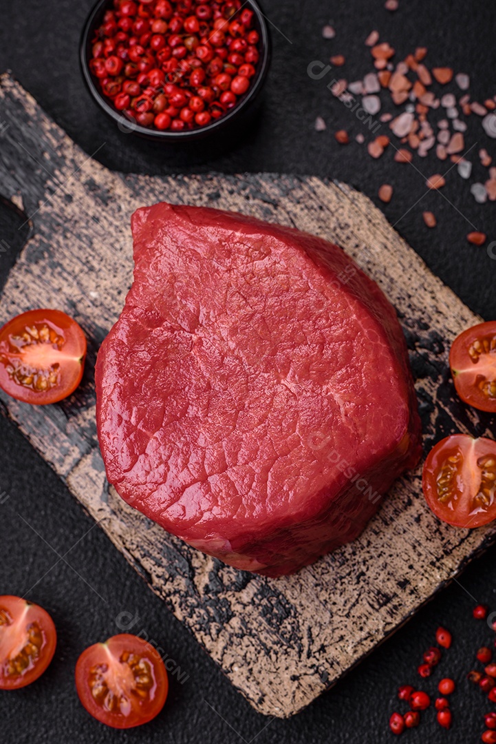 Carne crua fresca e suculenta com sal, especiarias e ervas sobre um fundo de concreto texturizado escuro