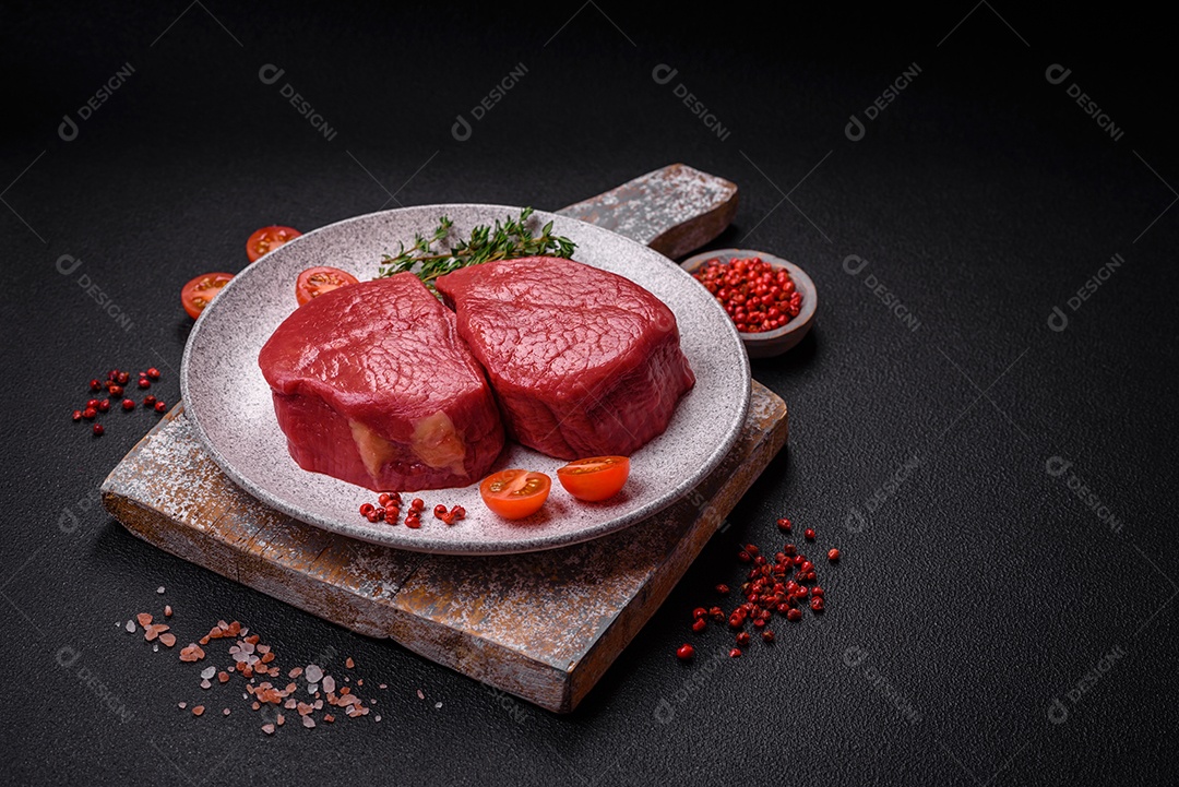 Carne crua fresca e suculenta com sal, especiarias e ervas sobre um fundo de concreto texturizado escuro