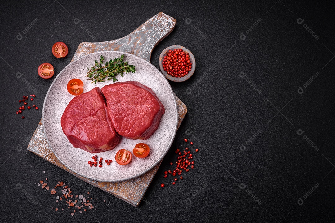 Carne crua fresca e suculenta com sal, especiarias e ervas sobre um fundo de concreto texturizado escuro