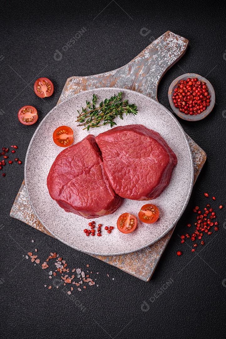 Carne crua fresca e suculenta com sal, especiarias e ervas sobre um fundo de concreto texturizado escuro