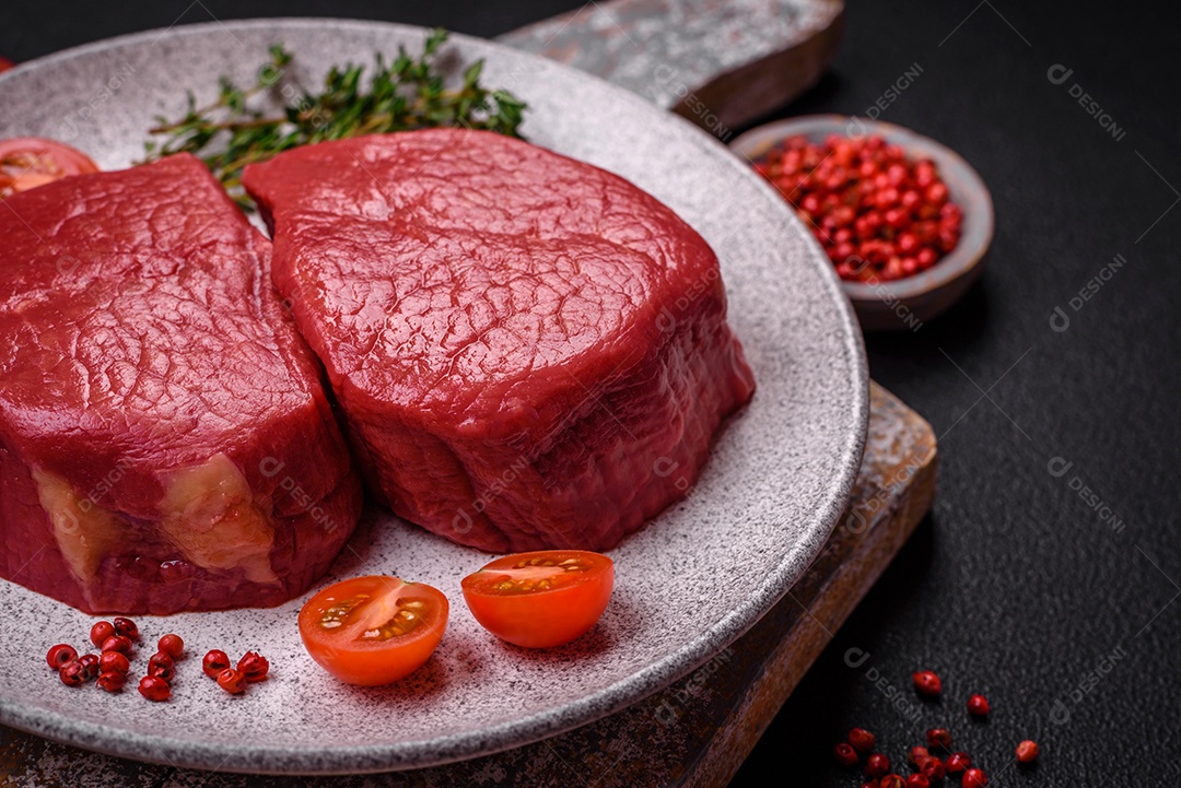 Carne crua fresca e suculenta com sal, especiarias e ervas sobre um fundo de concreto texturizado escuro