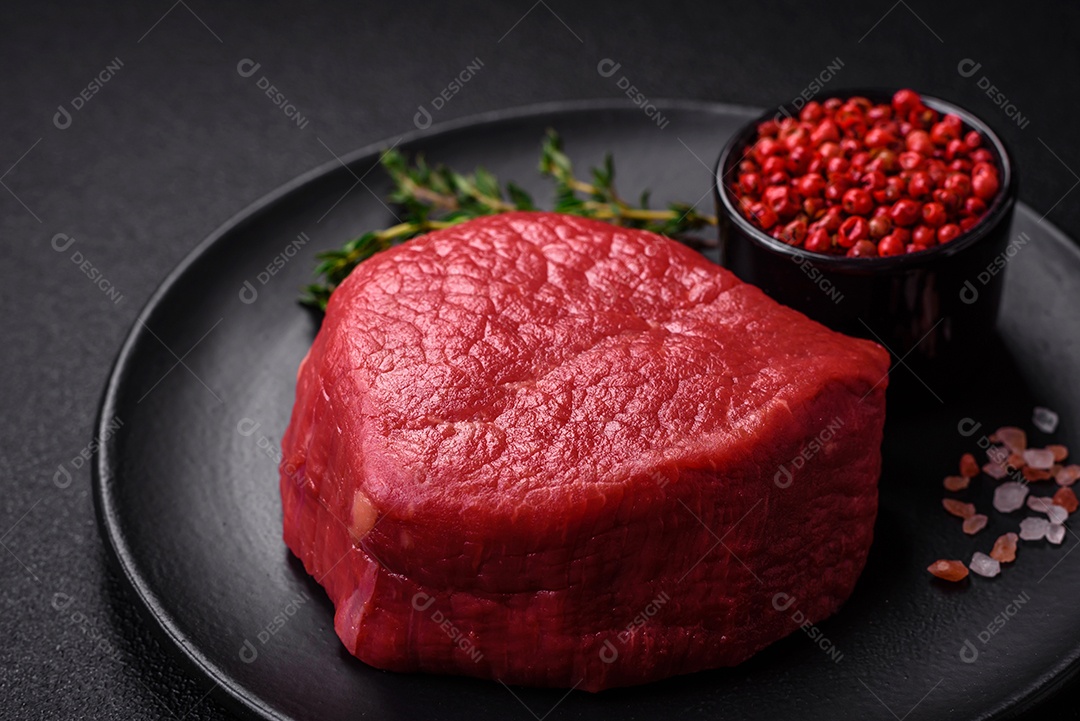 Carne crua fresca e suculenta com sal, especiarias e ervas sobre um fundo de concreto texturizado escuro