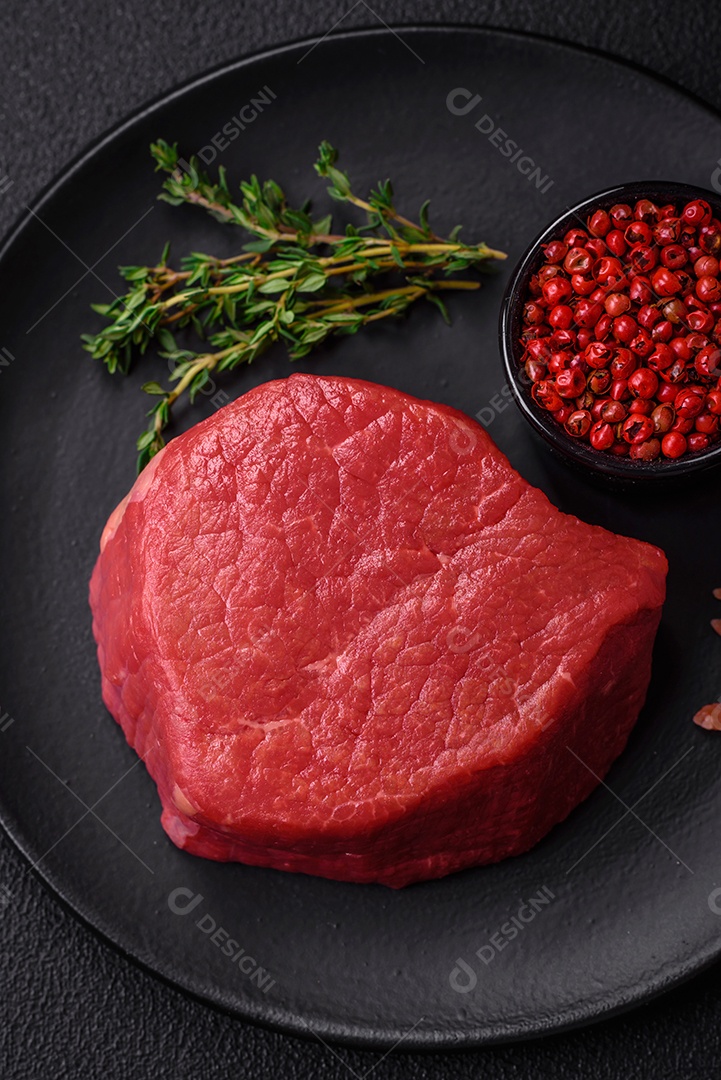 Carne crua fresca e suculenta com sal, especiarias e ervas sobre um fundo de concreto texturizado escuro