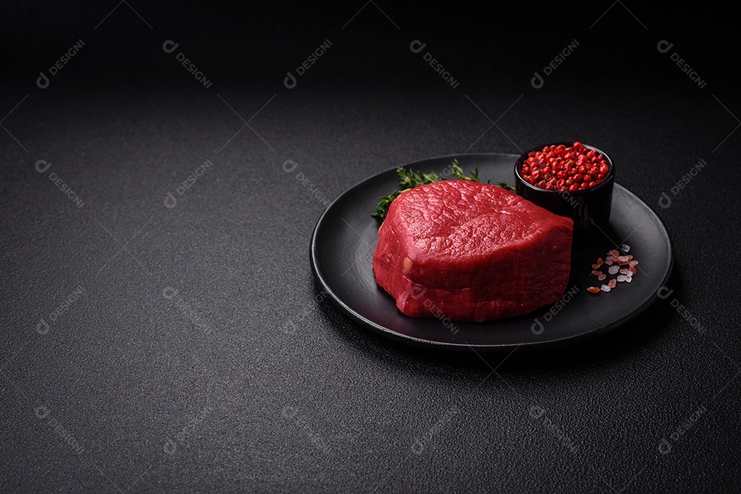 Carne crua fresca e suculenta com sal, especiarias e ervas sobre um fundo de concreto texturizado escuro