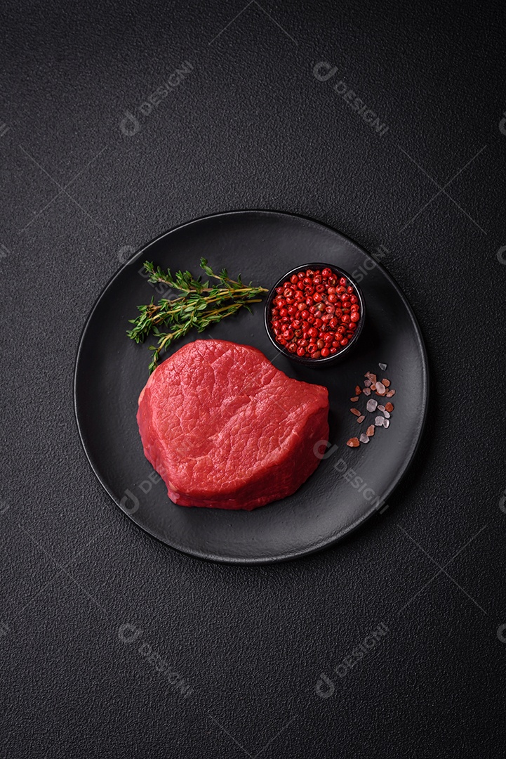 Carne crua fresca e suculenta com sal, especiarias e ervas sobre um fundo de concreto texturizado escuro