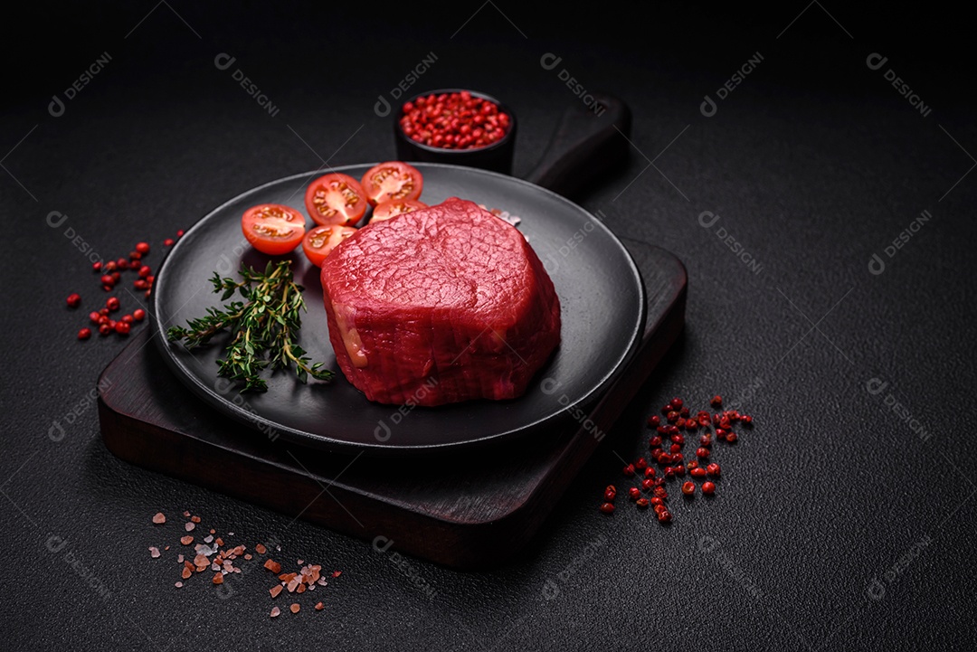 Carne crua fresca e suculenta com sal, especiarias e ervas sobre um fundo de concreto texturizado escuro