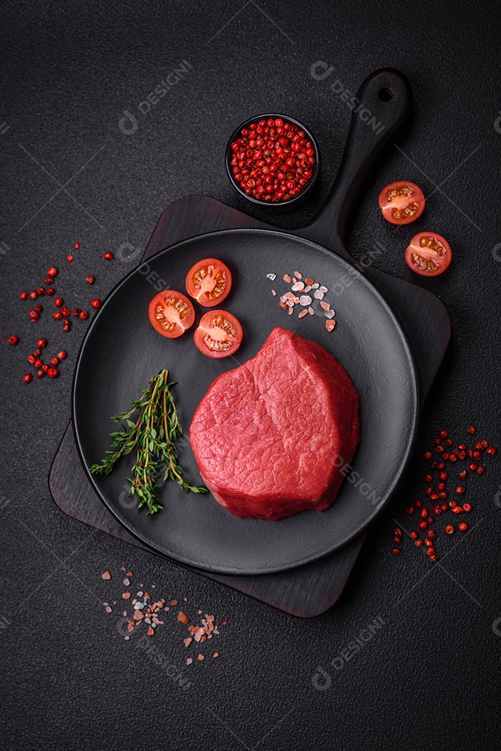 Carne crua fresca e suculenta com sal, especiarias e ervas sobre um fundo de concreto texturizado escuro