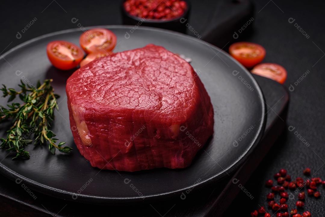Carne crua fresca e suculenta com sal, especiarias e ervas sobre um fundo de concreto texturizado escuro