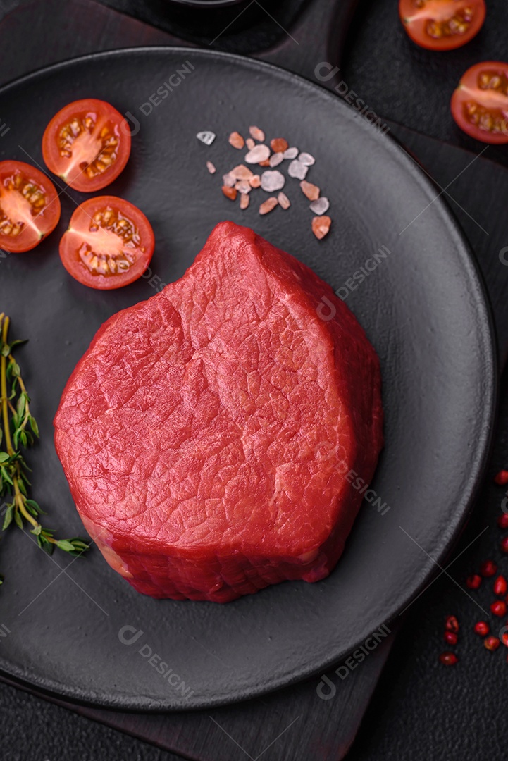 Carne crua fresca e suculenta com sal, especiarias e ervas sobre um fundo de concreto texturizado escuro