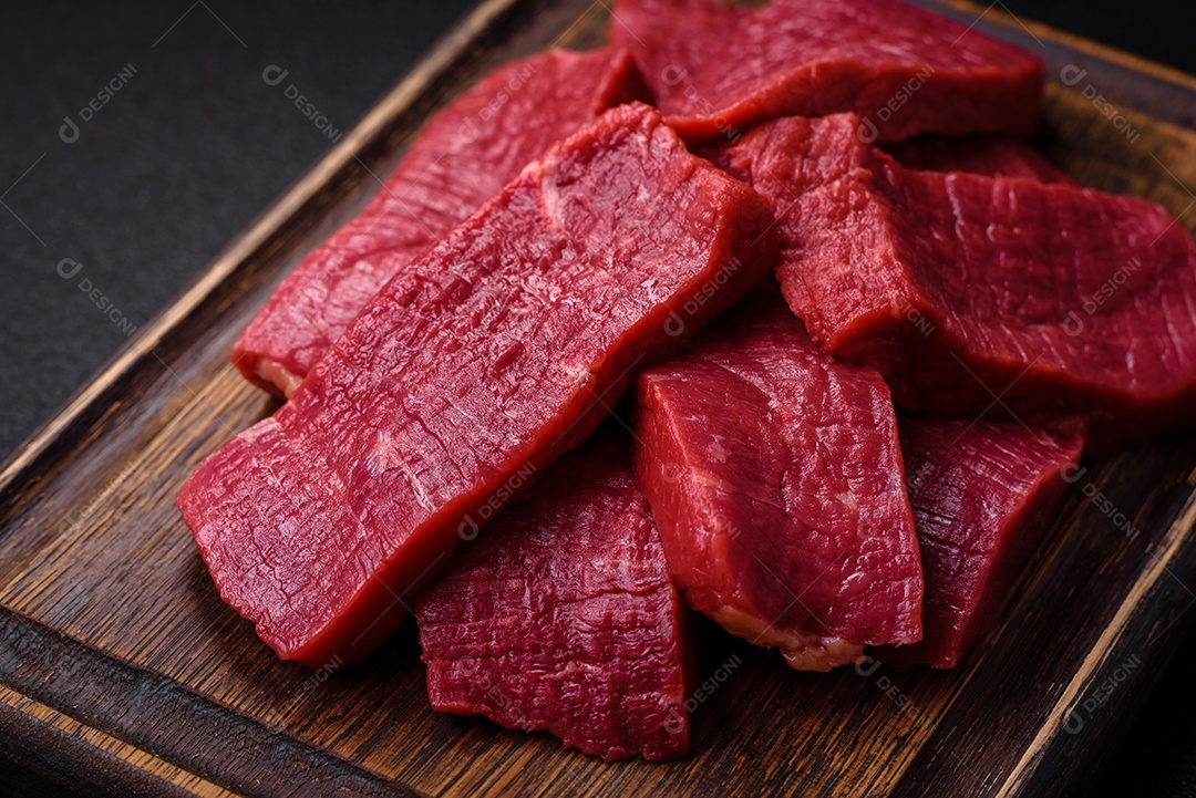 Carne crua fresca e suculenta com sal, especiarias e ervas sobre um fundo de concreto texturizado escuro