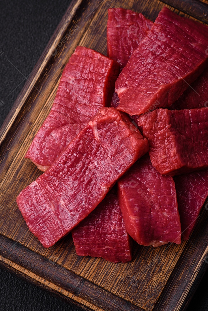 Carne crua fresca e suculenta com sal, especiarias e ervas sobre um fundo de concreto texturizado escuro