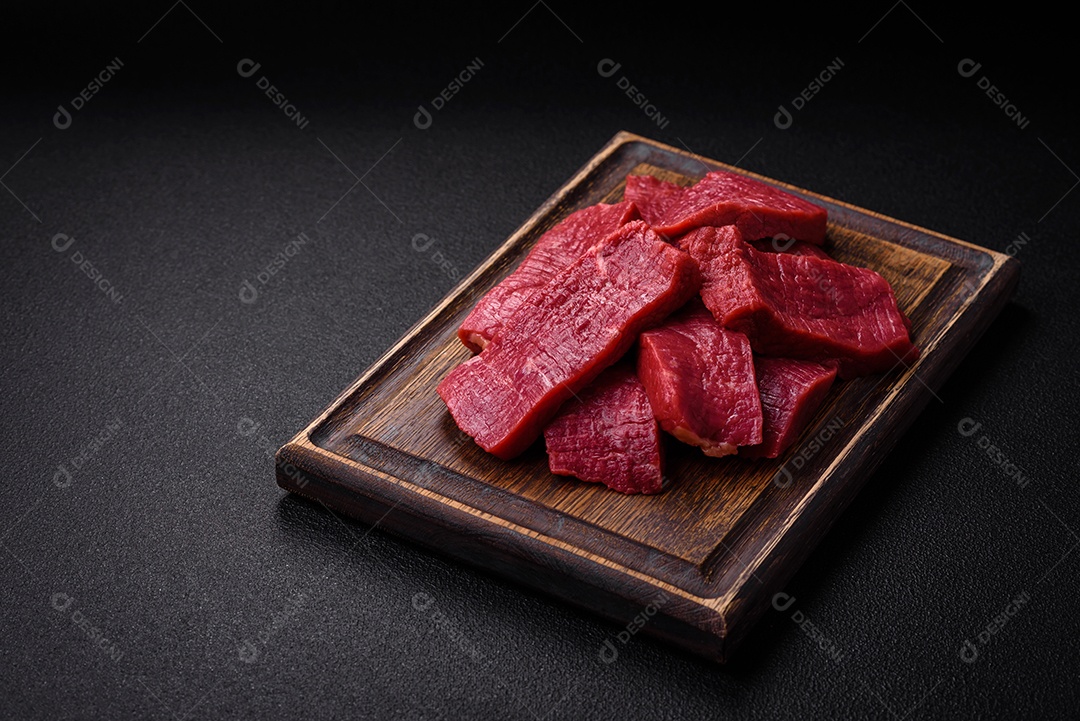 Carne crua fresca e suculenta com sal, especiarias e ervas sobre um fundo de concreto texturizado escuro