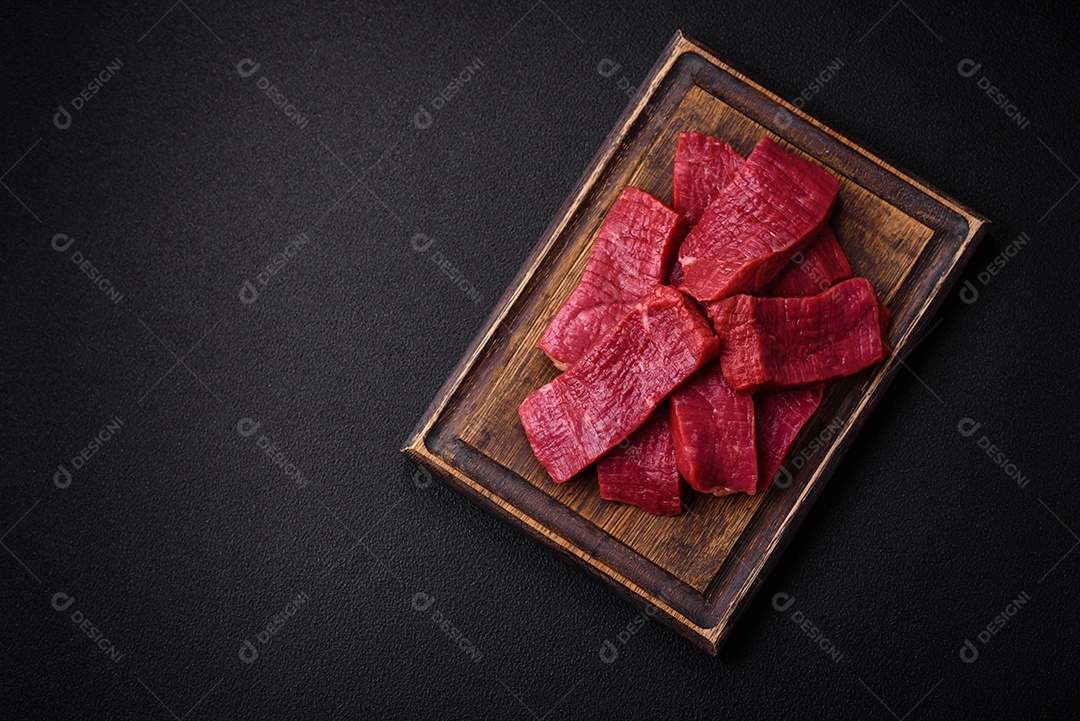 Carne crua fresca e suculenta com sal, especiarias e ervas sobre um fundo de concreto texturizado escuro