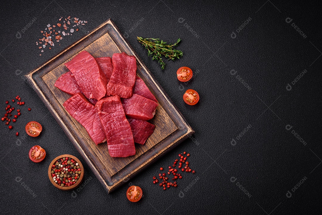 Carne crua fresca e suculenta com sal, especiarias e ervas sobre um fundo de concreto texturizado escuro