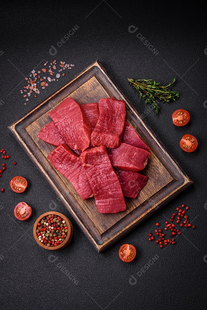 Carne crua fresca e suculenta com sal, especiarias e ervas sobre um fundo de concreto texturizado escuro