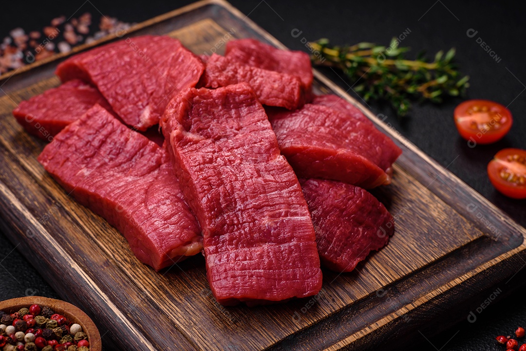 Carne crua fresca e suculenta com sal, especiarias e ervas sobre um fundo de concreto texturizado escuro