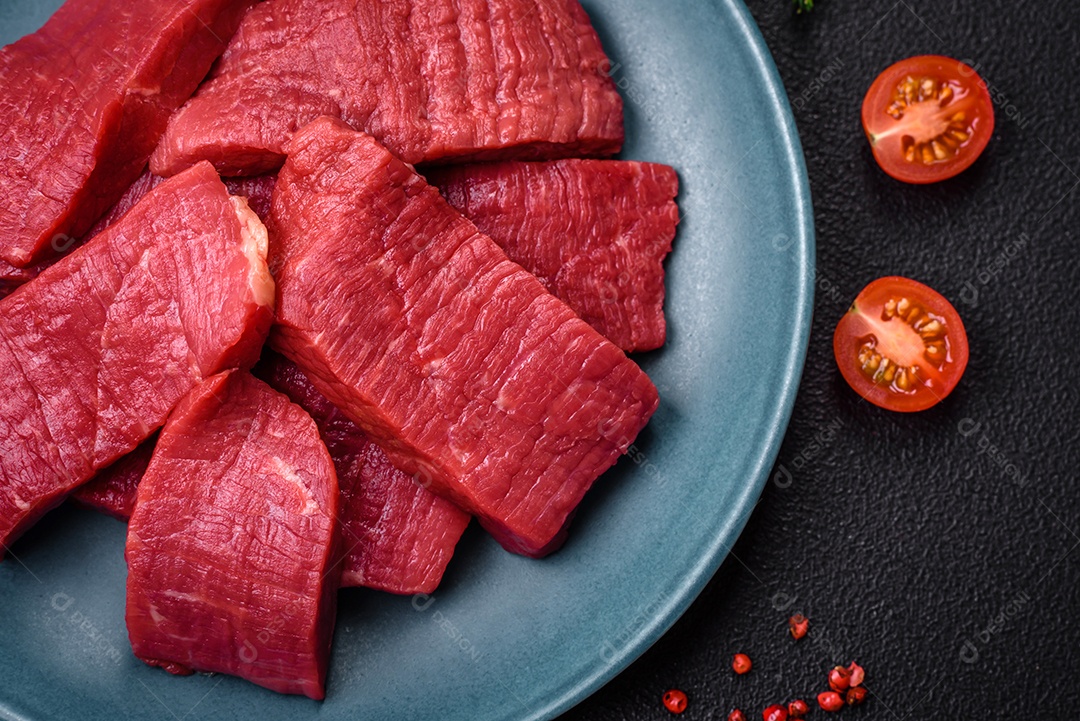 Carne crua fresca e suculenta com sal, especiarias e ervas sobre um fundo de concreto texturizado escuro