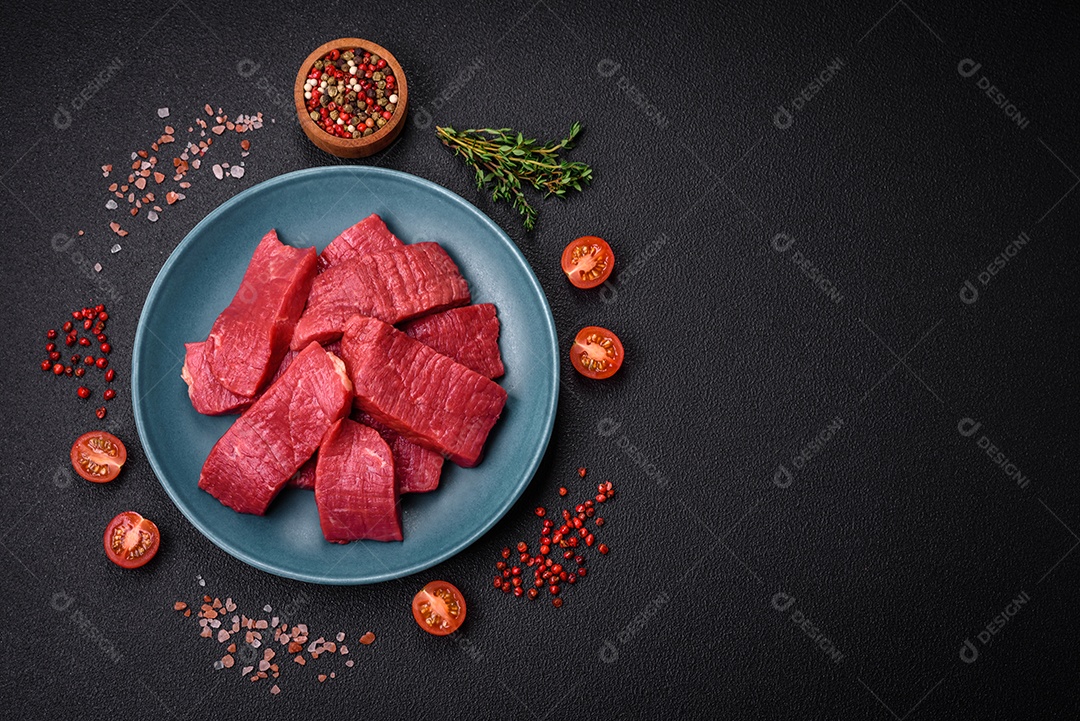 Carne crua fresca e suculenta com sal, especiarias e ervas sobre um fundo de concreto texturizado escuro