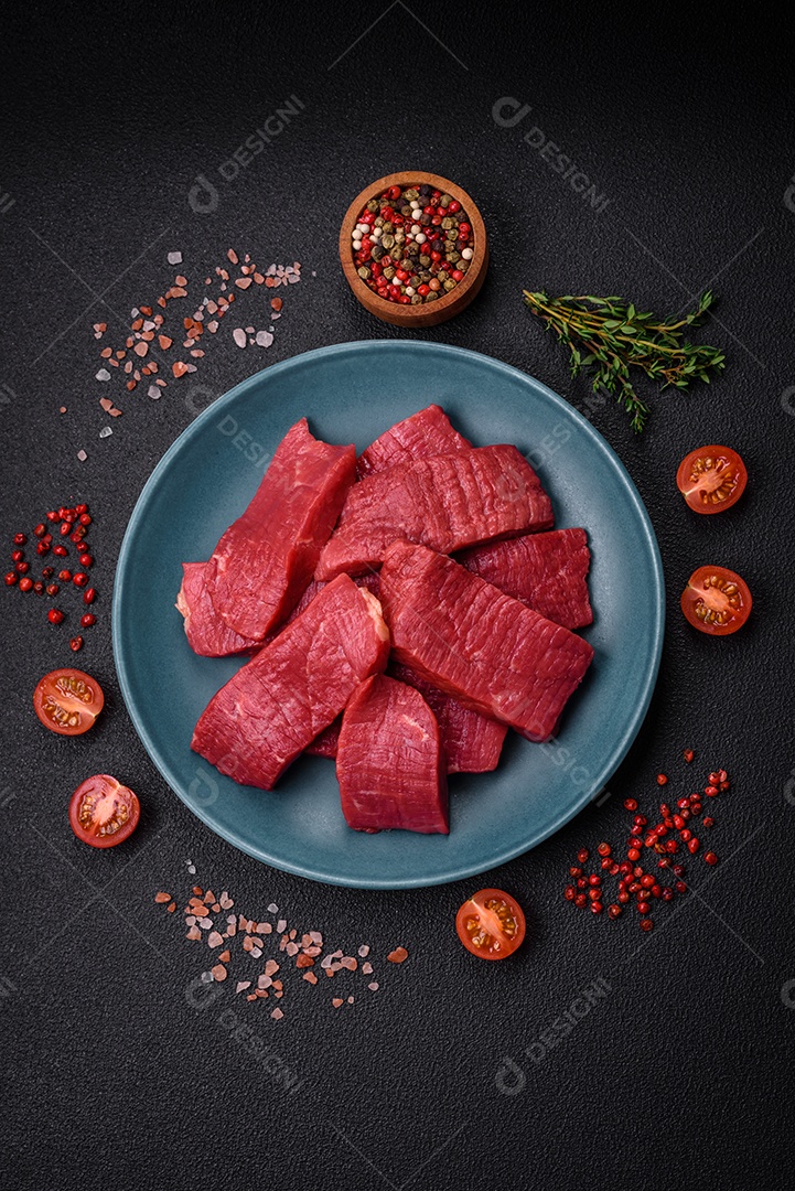 Carne crua fresca e suculenta com sal, especiarias e ervas sobre um fundo de concreto texturizado escuro