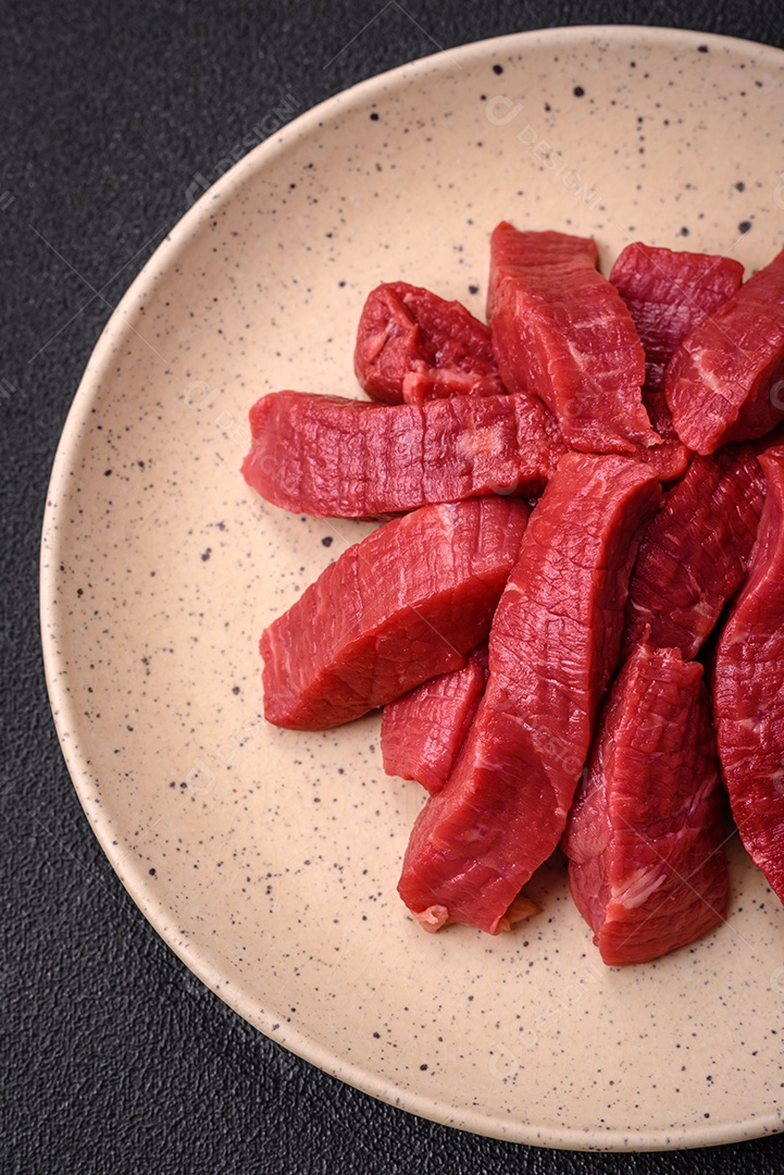 Carne crua fresca e suculenta com sal, especiarias e ervas sobre um fundo de concreto texturizado escuro