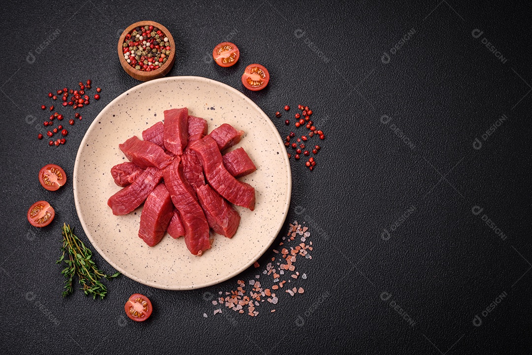 Carne crua fresca e suculenta com sal, especiarias e ervas sobre um fundo de concreto texturizado escuro