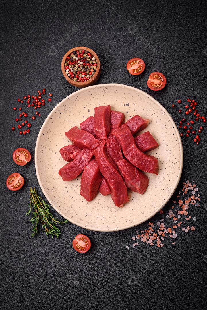 Carne crua fresca e suculenta com sal, especiarias e ervas sobre um fundo de concreto texturizado escuro