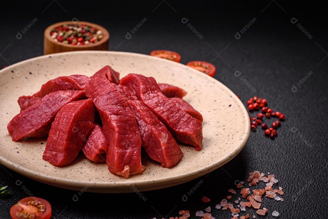 Carne crua fresca e suculenta com sal, especiarias e ervas sobre um fundo de concreto texturizado escuro