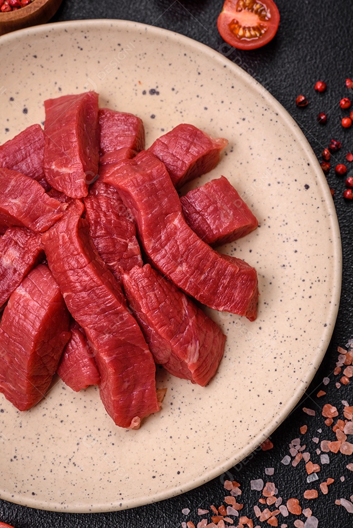 Carne crua fresca e suculenta com sal, especiarias e ervas sobre um fundo de concreto texturizado escuro