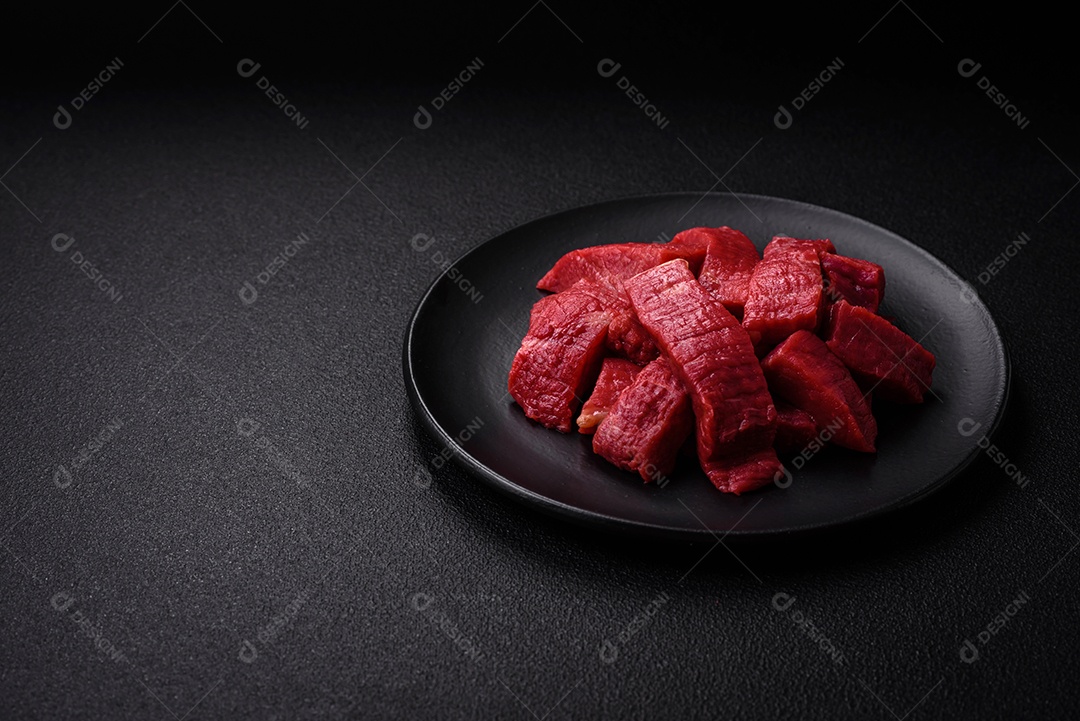 Carne crua fresca e suculenta com sal, especiarias e ervas sobre um fundo de concreto texturizado escuro