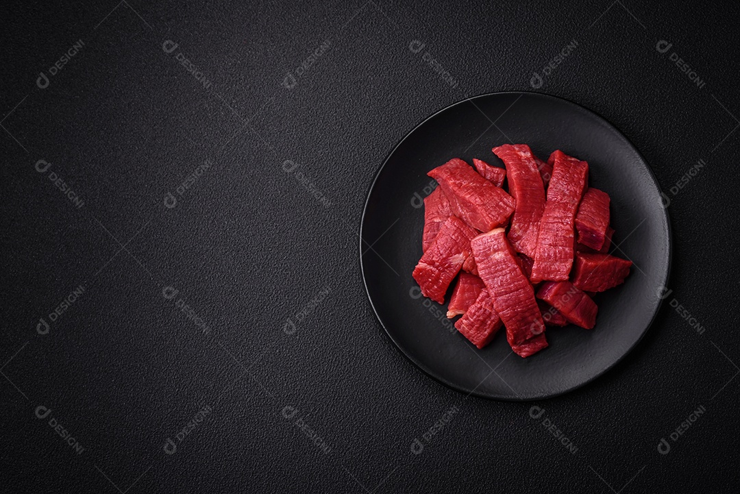 Carne crua fresca e suculenta com sal, especiarias e ervas sobre um fundo de concreto texturizado escuro