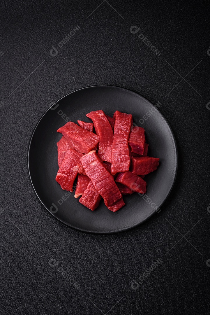 Carne crua fresca e suculenta com sal, especiarias e ervas sobre um fundo de concreto texturizado escuro