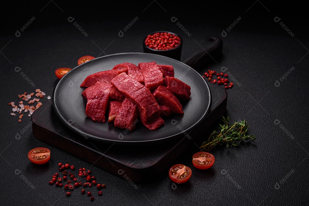 Carne crua fresca e suculenta com sal, especiarias e ervas sobre um fundo de concreto texturizado escuro