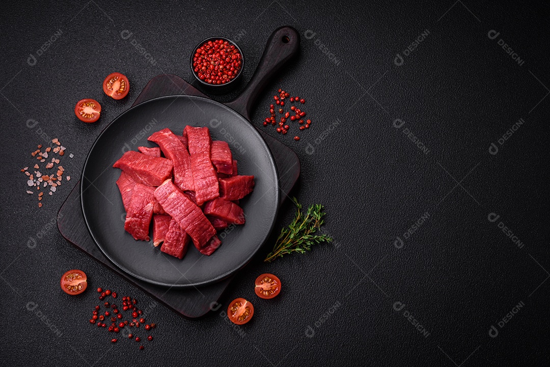 Carne crua fresca e suculenta com sal, especiarias e ervas sobre um fundo de concreto texturizado escuro