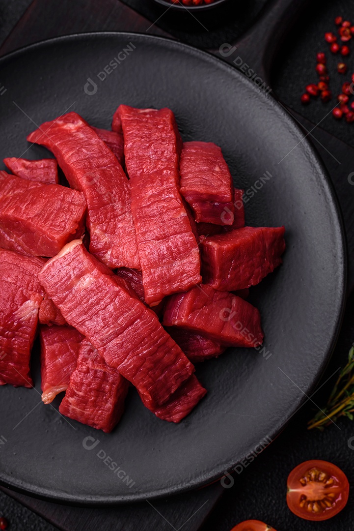 Carne crua fresca e suculenta com sal, especiarias e ervas sobre um fundo de concreto texturizado escuro