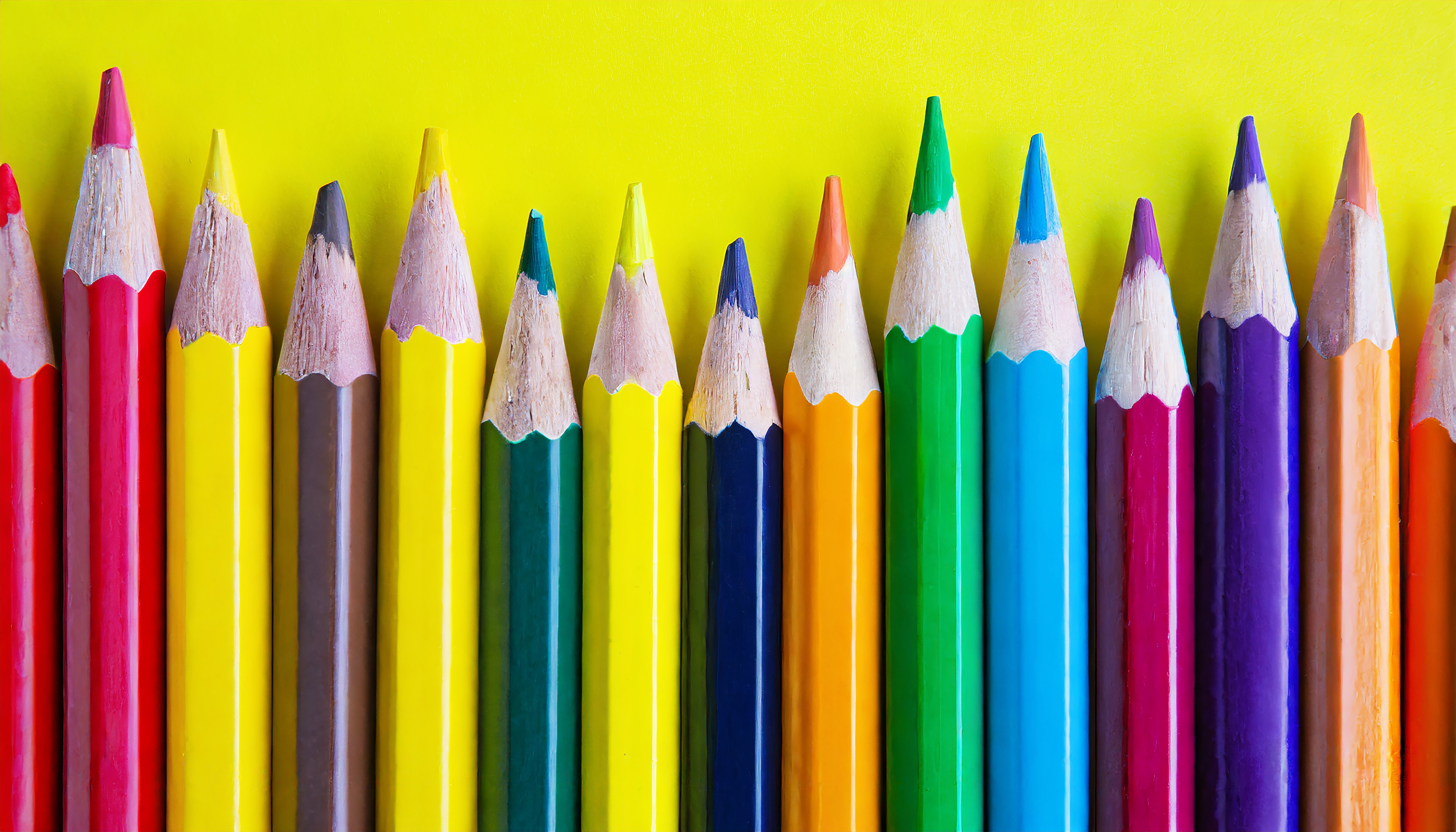 Uma fileira de lápis de cor sobre um fundo amarelo