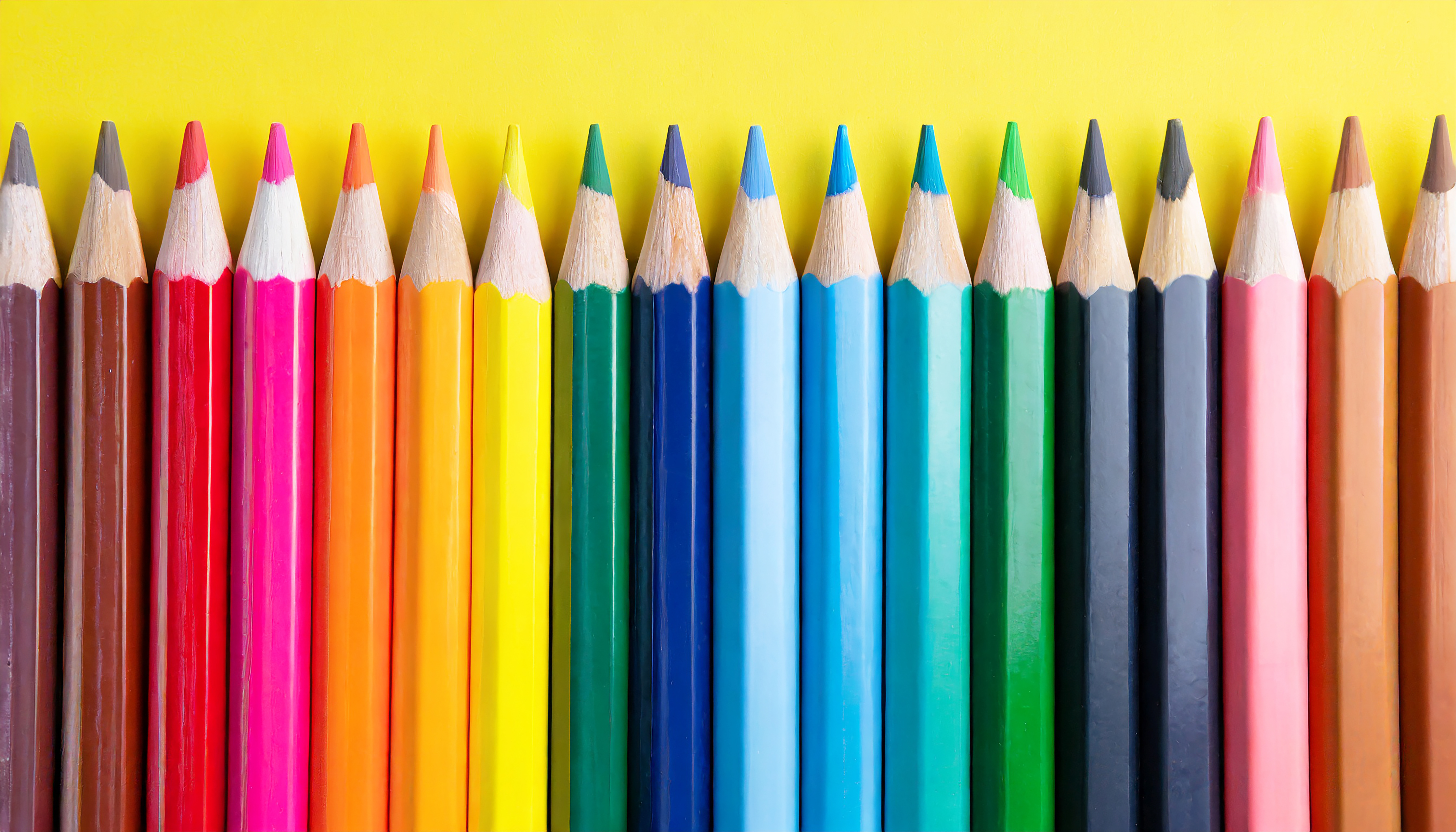 Uma fileira de lápis de cor sobre um fundo amarelo